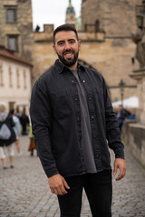 Fototapeta na wymiar Man traveler visiting Charles Bridge in Prague wearing dark colored clothing.