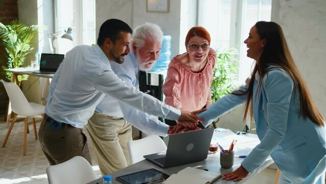 Business people or company employes stacking hands in a modern office and cheering together, celebrate a success.