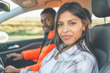 Beautiful happy young loving couple holding hands and smiling while sitting in their first car. Buy your first car concept toned image