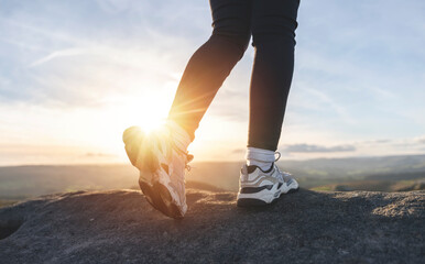 Close up of hiker in trainers trekking in the mountains at sunset. Concept for exercising, fitness...