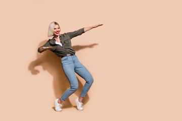Photo of sweet excited lady wear khaki shirt dancing having fun empty space isolated beige color background