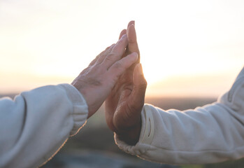 Hands of white man and black african american man gently and softly touching each other at sunset....
