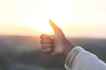 Man giving thumb up to at sunset nature background. Enjoy hiking and exploring new places concept...