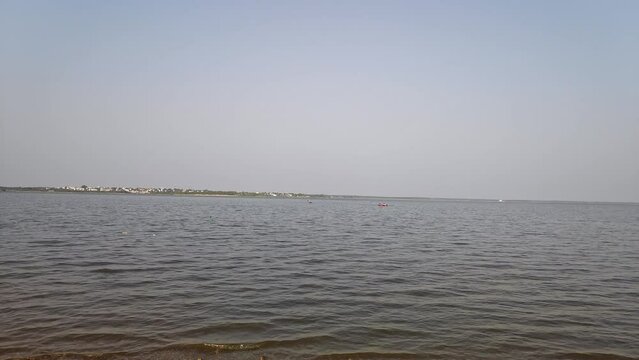 A wide view shows faraway tourists rafting in small boats in a large lake