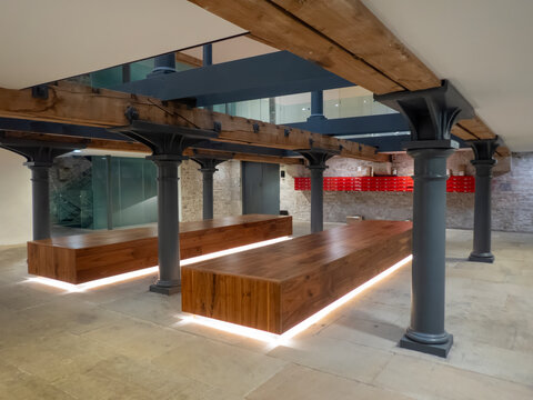 Industrial heritage interior; a renovated building with iron support columns, stone floors and large wooden beams.