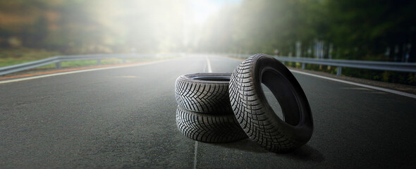 Winter tires on a asphalt road. Four wheel off. Change a summer tyre. Forest road with trees in blurred background. Change for new tire.