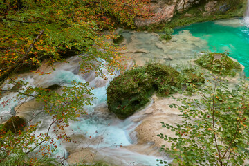 Naklejka na ściany i meble The waterfalls and crystal clear, blue, turquoise and green waters of the Nacedero del Urederra, with its beech forest with its autumn colors in the Sierra de Urbasa-Andía. Navarre. Spain