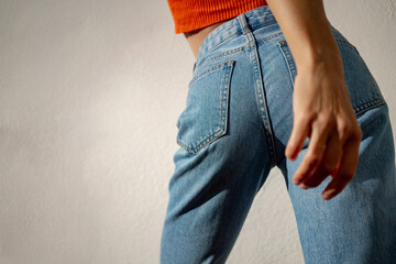 Beautiful athletic girl in blue jeans and an orange T-shirt. View from behind