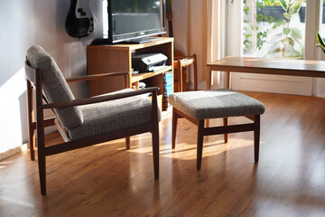 Armchair with Ottoman Danish Design in a Cosy Modern Furnished Living Room 60s Style Interior with a Wall Shelf and a Typewriter in the Background Orange Lamp wooden floor