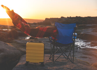 Blue beach chair, yellow  Suitcase, orange scarf in  the national park Peak District at sunrise on...