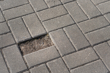 A damaged brick sidewalk with a noticeable hole in the middle