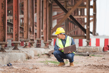 Engineer checking project at the building site, Man in hardhat with laptop at the infrastructure construction