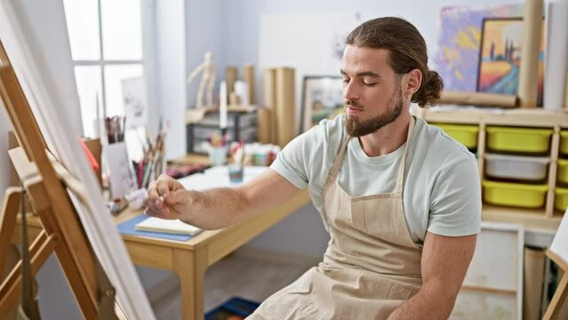 Young hispanic man artist smiling confident drawing relaxed at art studio
