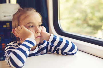 Little boy is traveling on the train. Kid travels on a train. Cute child looking out the train window.