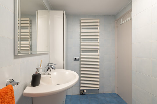 Radiator and cabinet in modern bathroom with vanity area