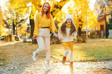 Lovely girl with her mom having fun on the walk. Autumn holidays, lifestyle.