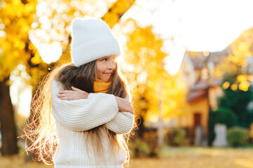 Cute child smiling and posing outdoors. Little girl wearing warm knitted sweater. Autumn kids fashion, lifestyle.
