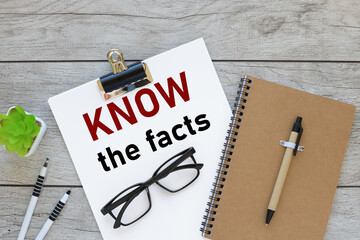 KNOW THE FACTS. white paper with text. plants in a pot. and pen and notepad