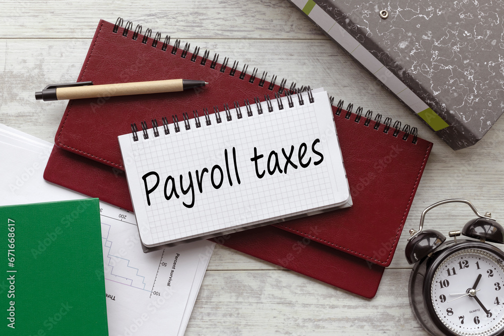 Aufkleber payroll taxes . text on a notebook on a diary. a table clock