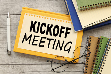 sheet of paper on a yellow notepad and glasses on the table. workbooks. text Kick-Off Meeting