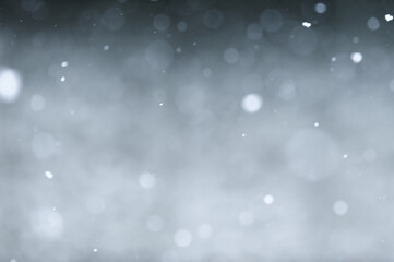 Bokeh of white snow on a square shape gray background. Falling snowflakes on night sky background,...