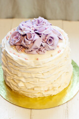 Elegant white cake with fondant ruffles and purple edible roses for birthday or wedding ceremony