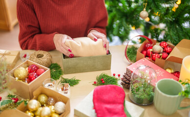 Woman in knitted sweater wrapping christmas presents with eco paper girl packing christmas gifts Xmas holiday concept