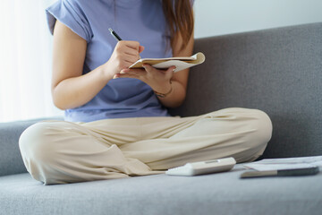 Asian woman holding paper document calculating money savings paying bills paying household bills tax insurance managing budget in living room