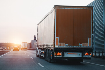 Modern white semi-trailer trucks on the highway driving in the right lane. Commercial vehicle for shipping and post delivery. Shipping of the goods on land with a door-to-door delivery process.
