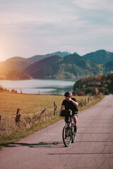 Fototapeta premium A cyclist riding a bike among the alpine mountains. Concept of the active healthy lifestyle. Mountain road with an alpine lake in the background. Vacation with nature. Concept of Human Recreation