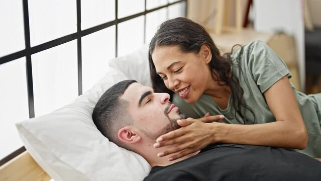 Beautiful couple in love, confidently enjoying morning kiss, relaxed lying on comfortable bedroom bed. smiling man & woman, together indoors, relishing fun, intimate moments at apartment.