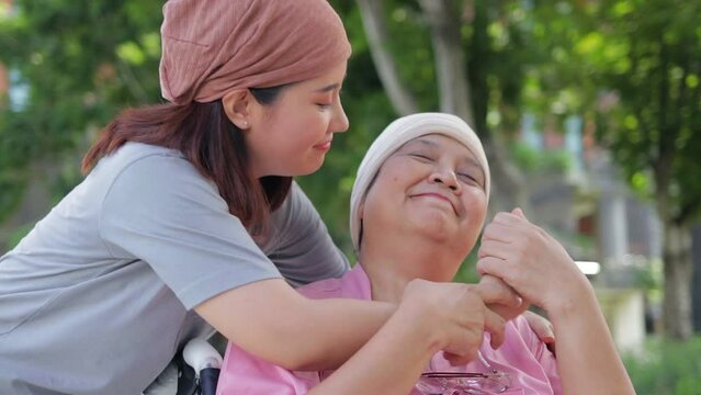 Portrait of a daughter taking care of her elderly mother who is sick with cancer, wearing a headscarf after chemotherapy together. Daughter encourages mother in treating disease. Cancer treatment