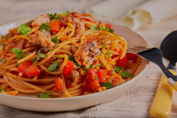 Sardine and spaghetti with vegetables in a tomato sauce and garnished with herbs.