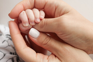 Parents' hands hold the fingers of a newborn baby. The hand of a mother and father close-up holds...