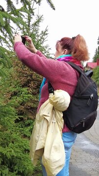 Woman with backpack takes photo with smartphone. Vertical Video