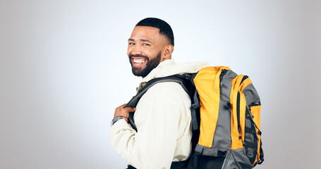 Man, happy portrait and hiking in studio with backpack and smile from travel and freedom with adventure. Camping, fitness and grey background and walking with trekking gear for vacation and holiday