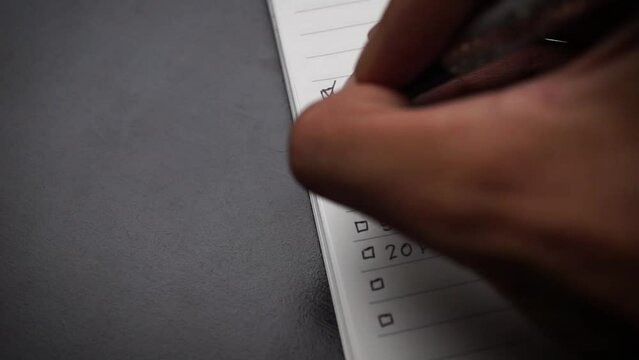 hand writing a list of personal health goals for self-development containing meditation, drinking water, sleeping early, eating healthy vegetables, push ups workout, and running training