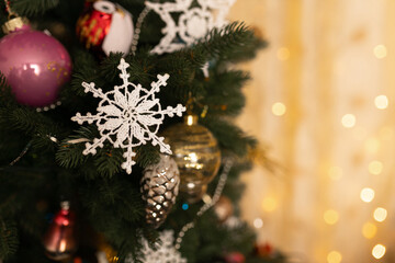 knitted white handmade snowflake with ornaments on Christmas tree at home