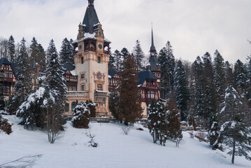 Peleș Castle in Sinaia, Romania with a snowy forrest behind