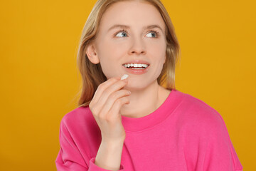 Happy young woman with bubble gum on yellow background
