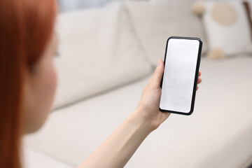 Woman using mobile phone indoors, closeup view