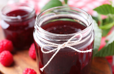 Glass jar of delicious raspberry jam on board, closeup