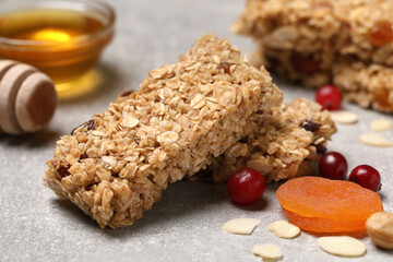 Tasty granola bars and ingredients on light grey table, closeup