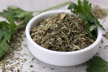 Dried parsley and fresh leaves on light grey table, closeup