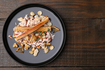 Plate with baked salsify roots, lemon and rice on wooden table, top view. Space for text