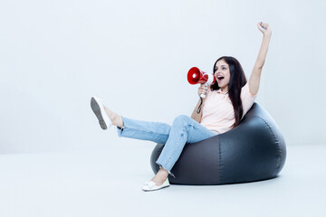 Excited Indian latin Female Announcing In Megaphone Sitting on Bean bag Advertisement sale concept