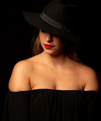 High contrast portrait of an attractive caucasian woman wearing black hat. Headshot of an adult