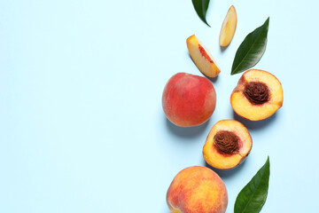 Delicious juicy peaches and leaves on light blue background, flat lay. Space for text