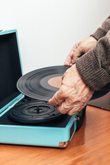 Vertical close up photo, senior adult man backside placing vinyl on a turntable Concept hobbies, art