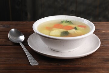 Tasty chicken soup with vegetables in bowl served on wooden table, closeup